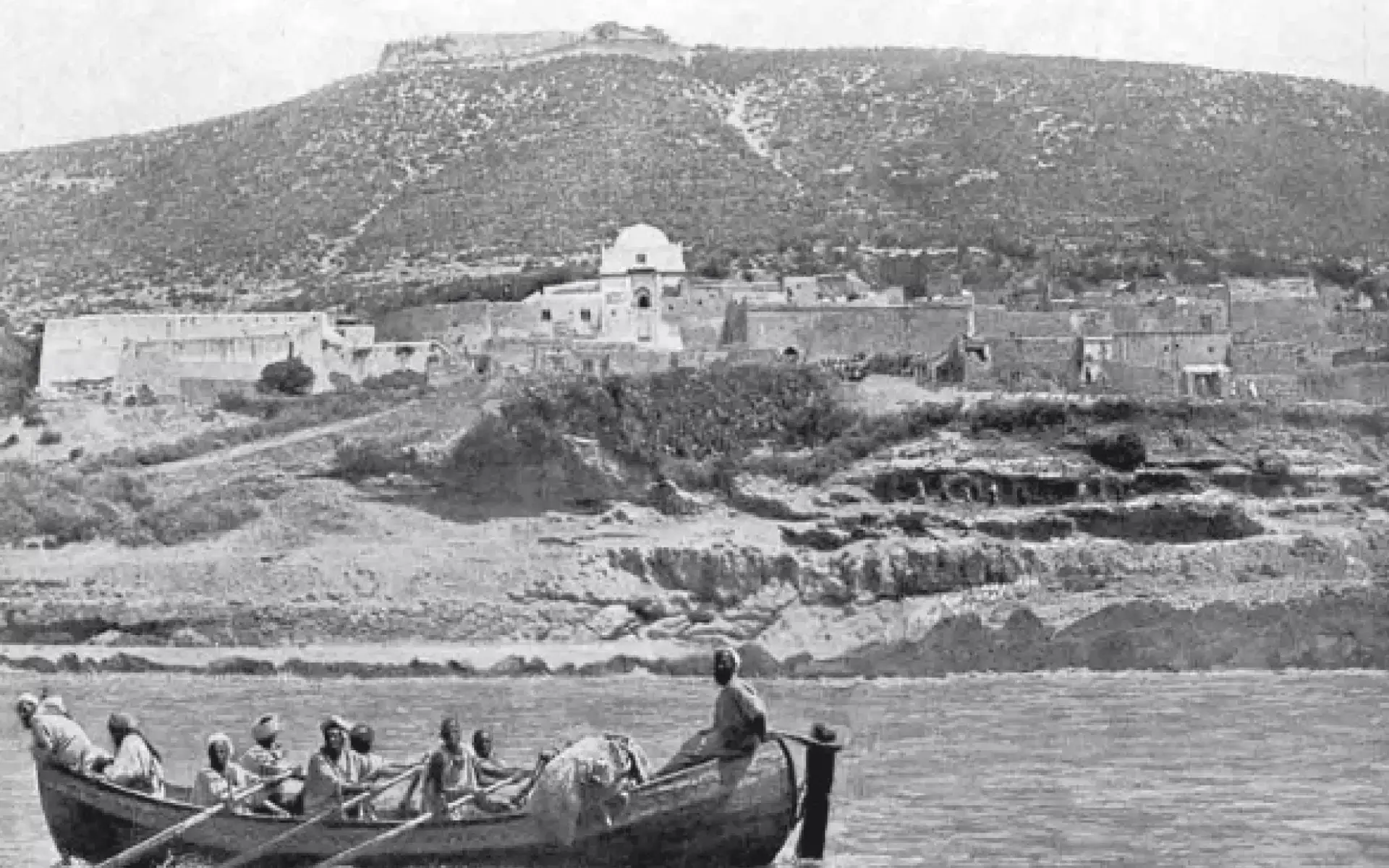 Vue historique du port d’Agadir avec des rameurs en barque et la Kasbah d’Agadir Oufella en arrière-plan
